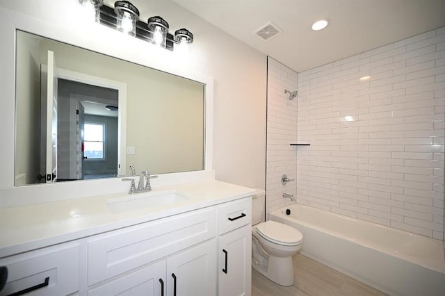 full bathroom featuring hardwood / wood-style floors, vanity, toilet, and tiled shower / bath