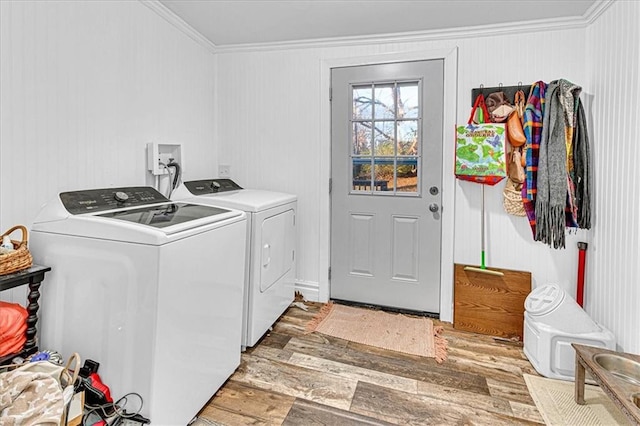 clothes washing area with washer and dryer, light hardwood / wood-style floors, and ornamental molding