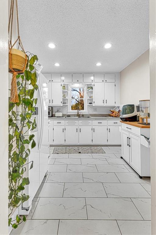 kitchen featuring white cabinets, pendant lighting, and a textured ceiling