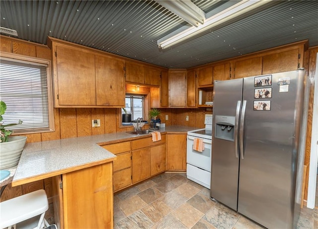 kitchen featuring a kitchen breakfast bar, sink, stainless steel refrigerator with ice dispenser, electric range, and kitchen peninsula