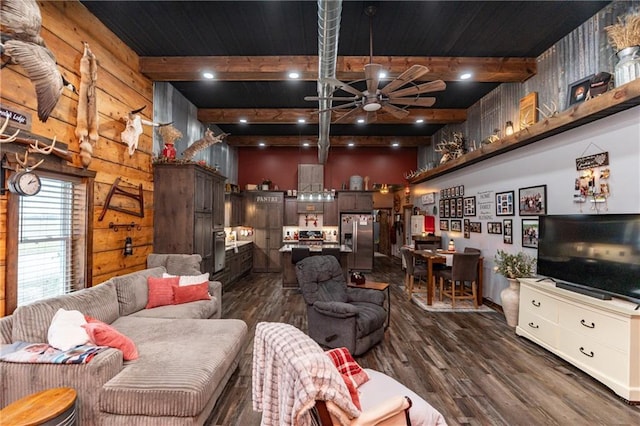 living room with beamed ceiling, ceiling fan, dark hardwood / wood-style floors, and wooden walls