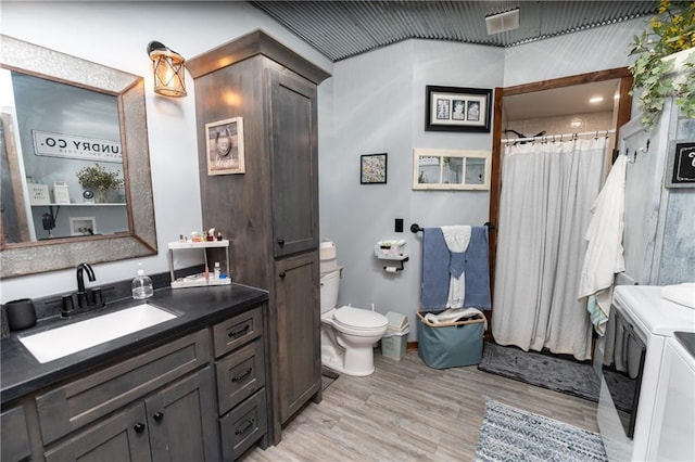 bathroom with walk in shower, vanity, hardwood / wood-style floors, independent washer and dryer, and toilet