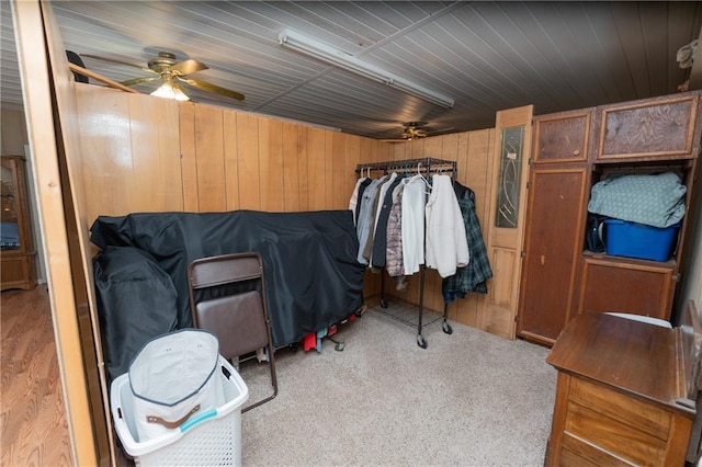 carpeted bedroom featuring ceiling fan and wood walls