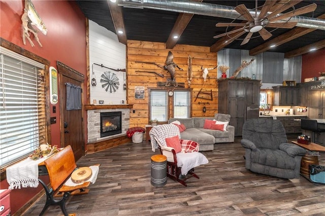 living room with ceiling fan, beam ceiling, a fireplace, dark hardwood / wood-style floors, and wood walls