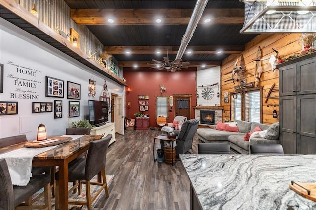 living room featuring a stone fireplace, ceiling fan, dark hardwood / wood-style flooring, and wooden ceiling