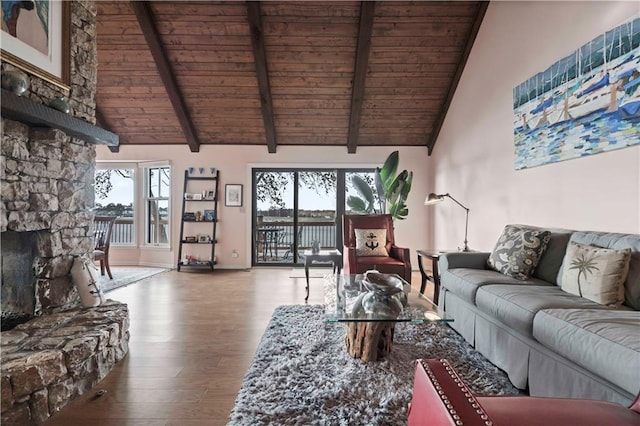 living room featuring hardwood / wood-style flooring, a healthy amount of sunlight, a stone fireplace, and high vaulted ceiling