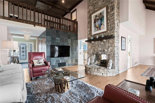 living room with hardwood / wood-style floors, beam ceiling, a fireplace, and a high ceiling