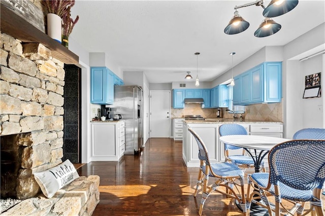 kitchen featuring dark hardwood / wood-style flooring, blue cabinets, backsplash, and appliances with stainless steel finishes