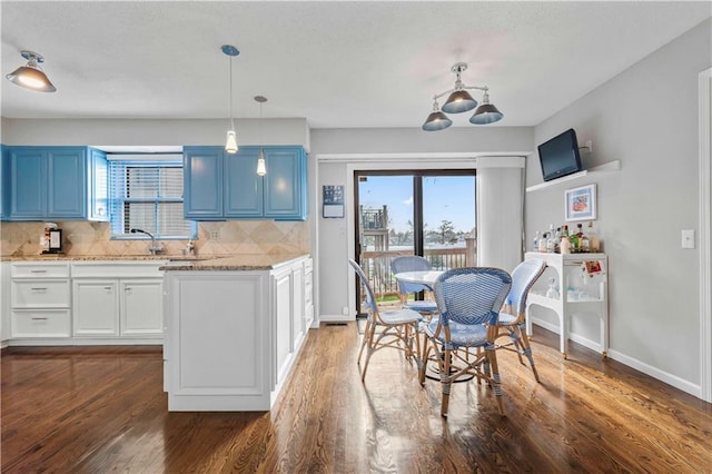 kitchen featuring decorative backsplash, blue cabinets, and hanging light fixtures