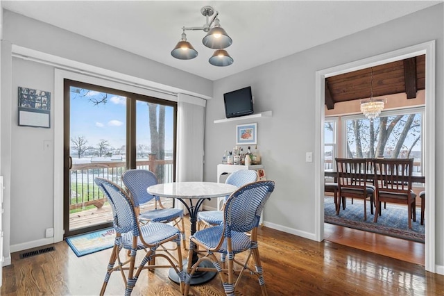 dining area featuring a healthy amount of sunlight, dark hardwood / wood-style floors, and a notable chandelier