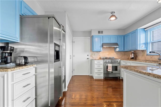 kitchen with light stone countertops, stainless steel appliances, blue cabinets, and dark wood-type flooring