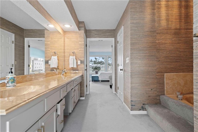 bathroom with a washtub, a textured ceiling, and vanity