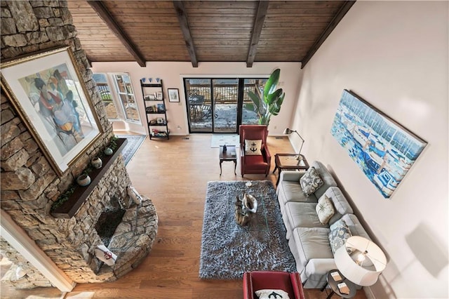 living room with hardwood / wood-style floors, beam ceiling, a stone fireplace, and wood ceiling