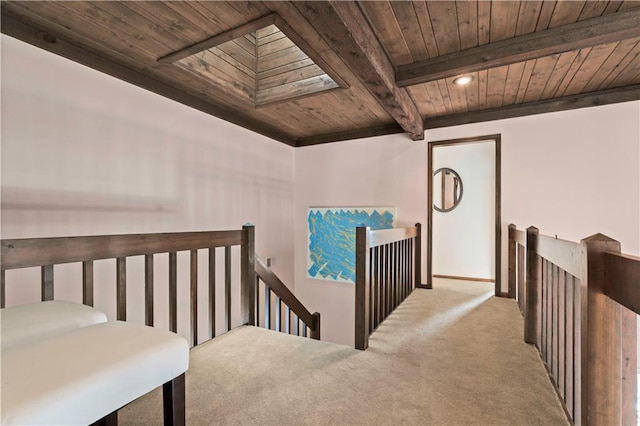 hall featuring a skylight, beamed ceiling, light colored carpet, and wood ceiling