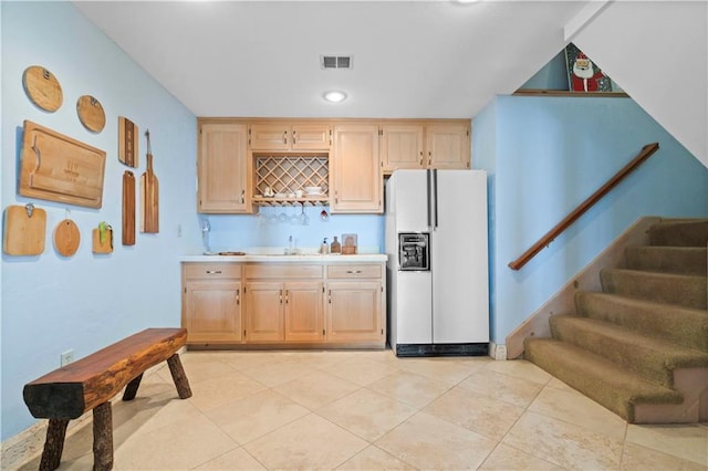 kitchen featuring light tile patterned floors, white refrigerator with ice dispenser, sink, and light brown cabinetry