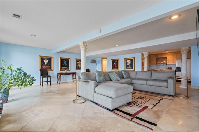 living room featuring beamed ceiling, ornate columns, and indoor bar