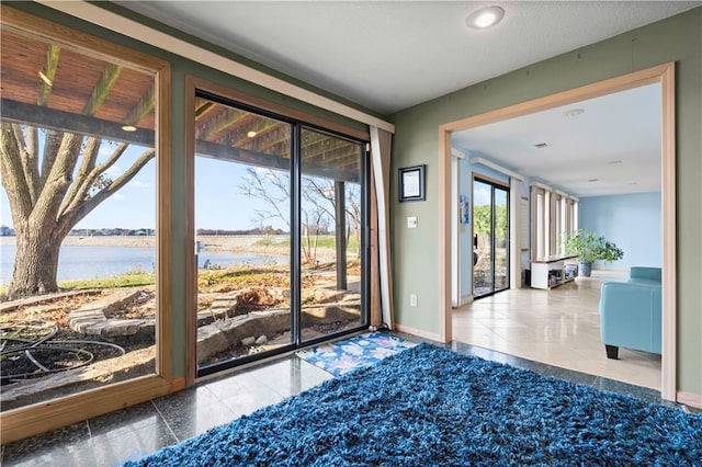 entryway with a water view, tile patterned floors, and a wealth of natural light