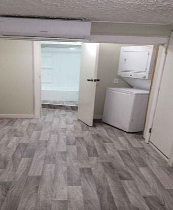 washroom featuring stacked washer and dryer, a textured ceiling, and light wood-type flooring