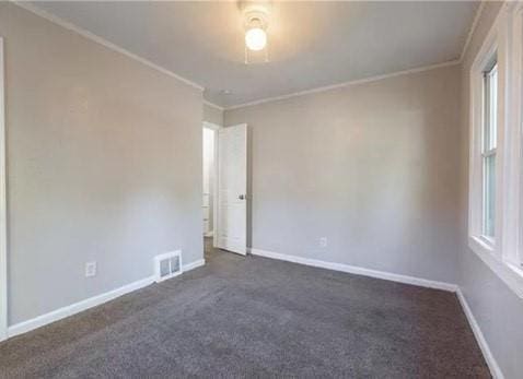 spare room with crown molding and dark colored carpet