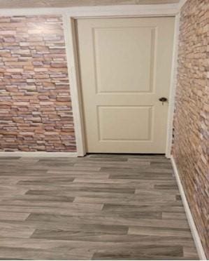 entryway with wood-type flooring and brick wall