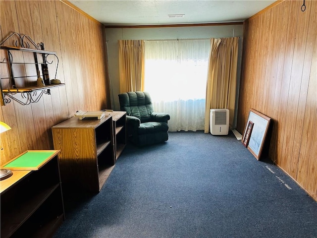 living area with wooden walls and dark carpet