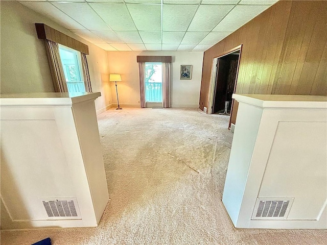 hallway with wood walls and light colored carpet