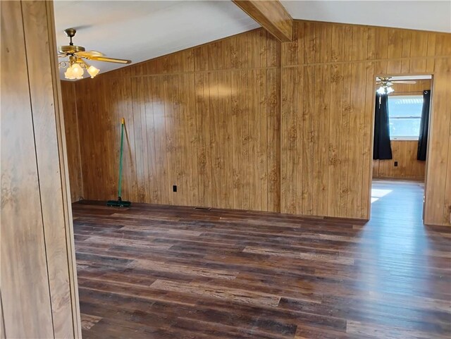 spare room with wood walls, lofted ceiling with beams, and dark hardwood / wood-style floors