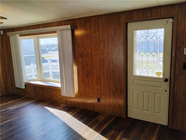 foyer entrance featuring dark hardwood / wood-style flooring and wooden walls