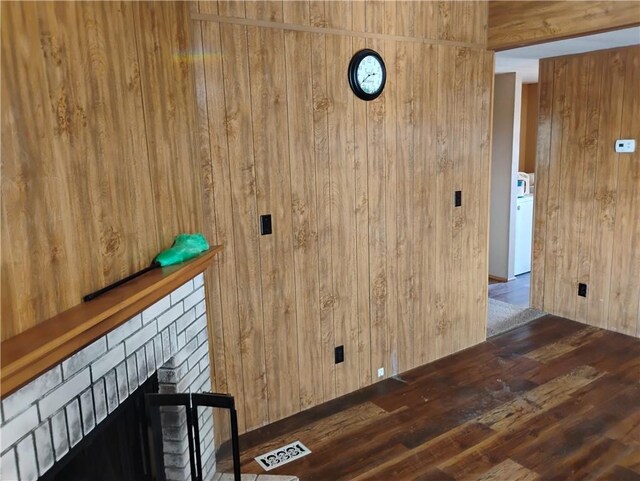 interior space featuring dark hardwood / wood-style floors, washer / clothes dryer, and wooden walls