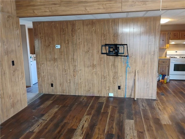 interior space with dark hardwood / wood-style flooring, washer / clothes dryer, and wood walls