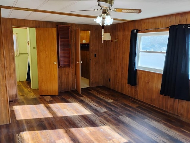 empty room with dark hardwood / wood-style floors, wood walls, and ceiling fan