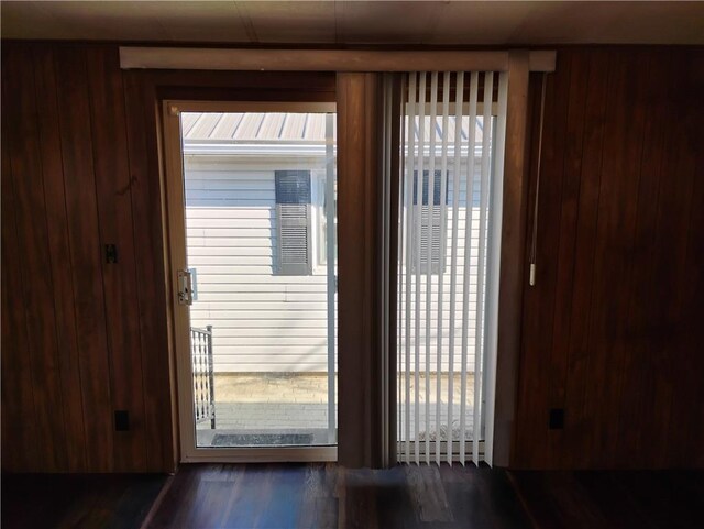 doorway to outside with wooden walls and dark hardwood / wood-style flooring