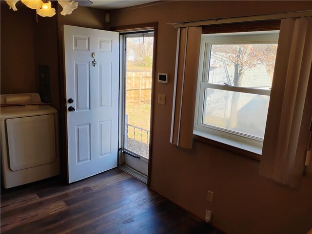 doorway to outside featuring washing machine and dryer, dark wood-type flooring, and a healthy amount of sunlight