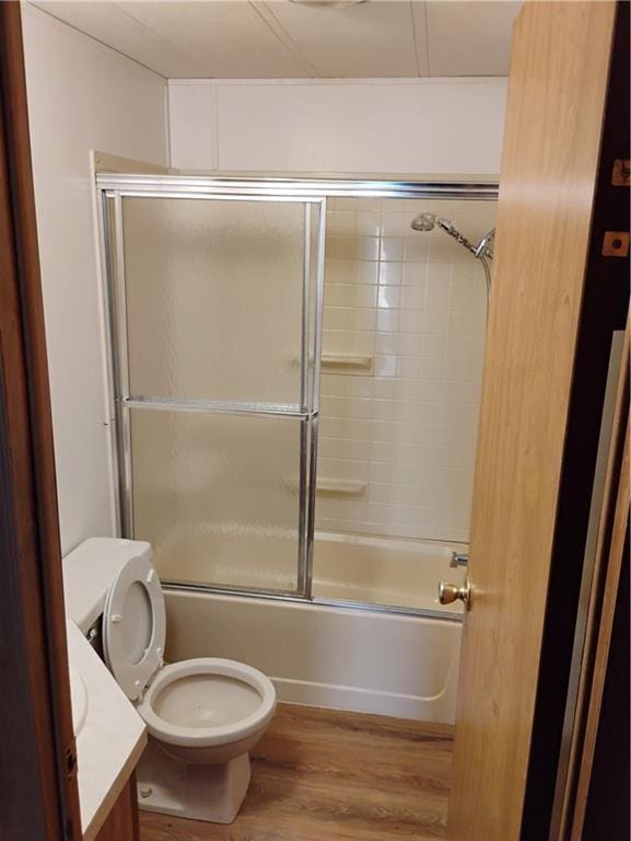 full bathroom featuring bath / shower combo with glass door, vanity, wood-type flooring, and toilet