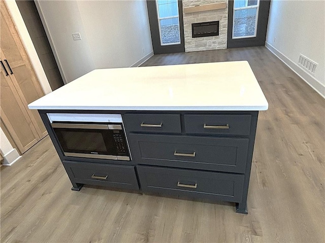 kitchen with a fireplace, light wood-type flooring, and a kitchen island