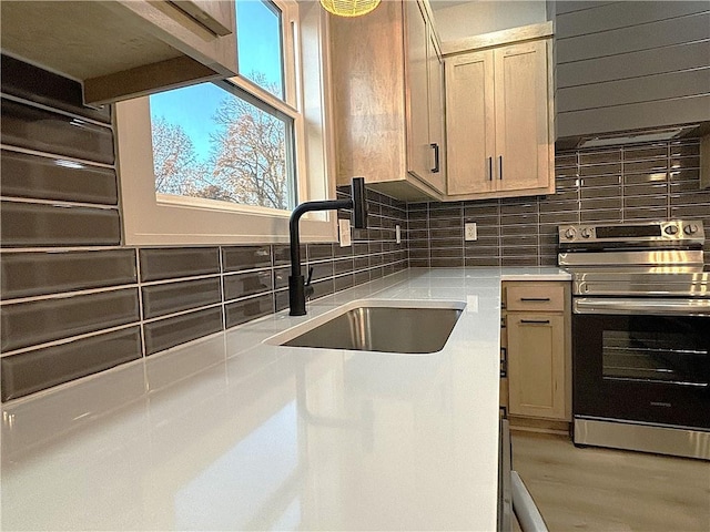 kitchen featuring light brown cabinets, light wood-type flooring, sink, and stainless steel stove