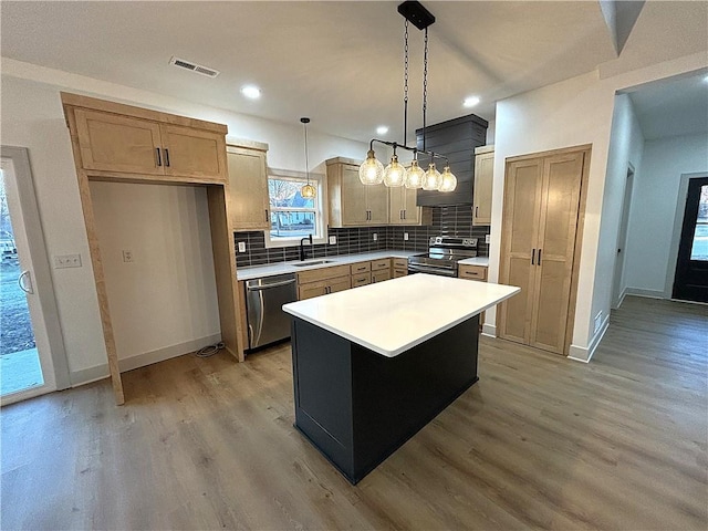 kitchen with a center island, sink, hanging light fixtures, light hardwood / wood-style flooring, and appliances with stainless steel finishes