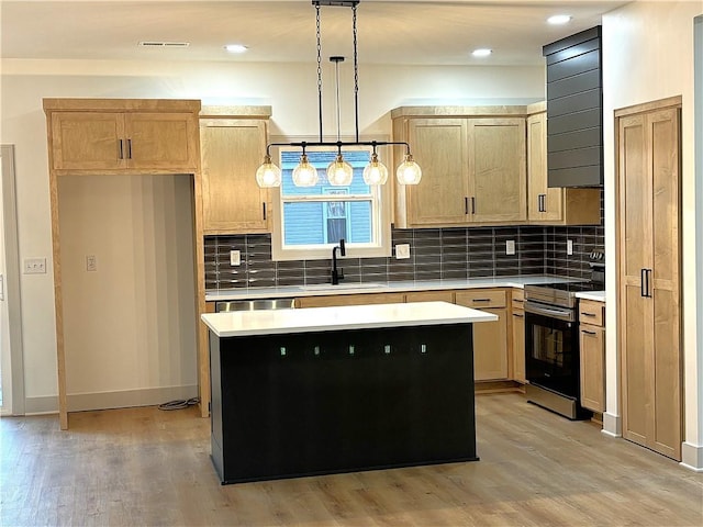 kitchen with a center island, stainless steel range with electric cooktop, sink, hanging light fixtures, and light wood-type flooring