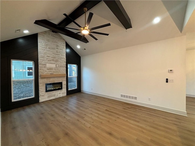 unfurnished living room with high vaulted ceiling, ceiling fan, a fireplace, beamed ceiling, and wood-type flooring