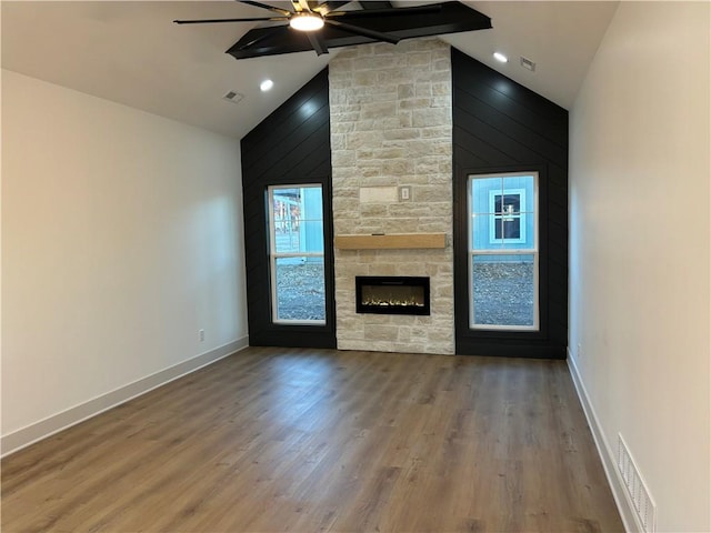 unfurnished living room featuring hardwood / wood-style floors, ceiling fan, a stone fireplace, and high vaulted ceiling