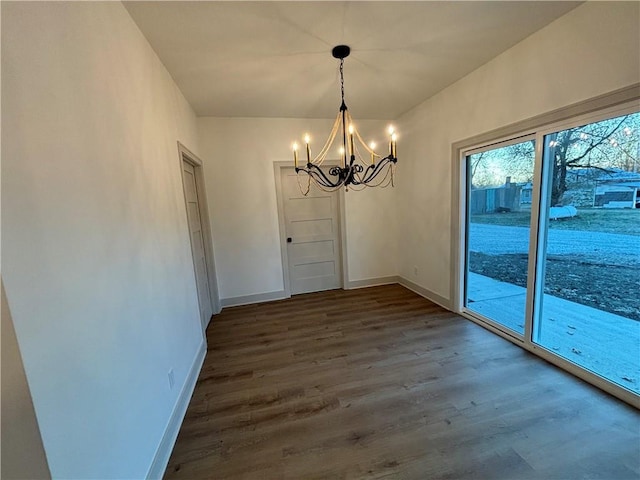 unfurnished dining area featuring dark hardwood / wood-style floors and an inviting chandelier