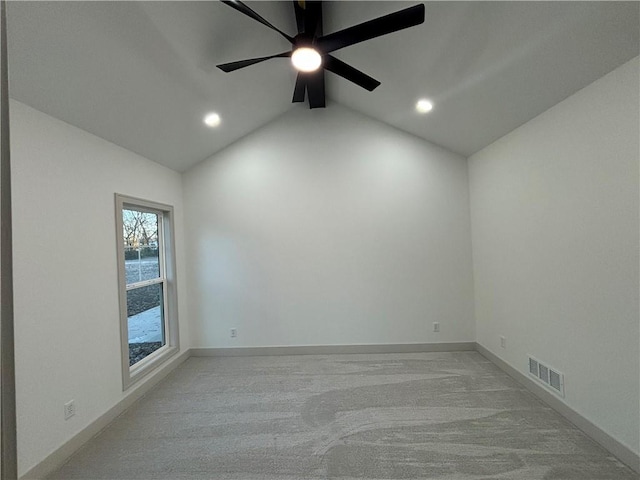 carpeted spare room featuring vaulted ceiling and ceiling fan