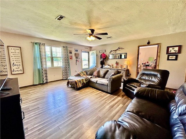 living room with ceiling fan, light hardwood / wood-style floors, and a textured ceiling