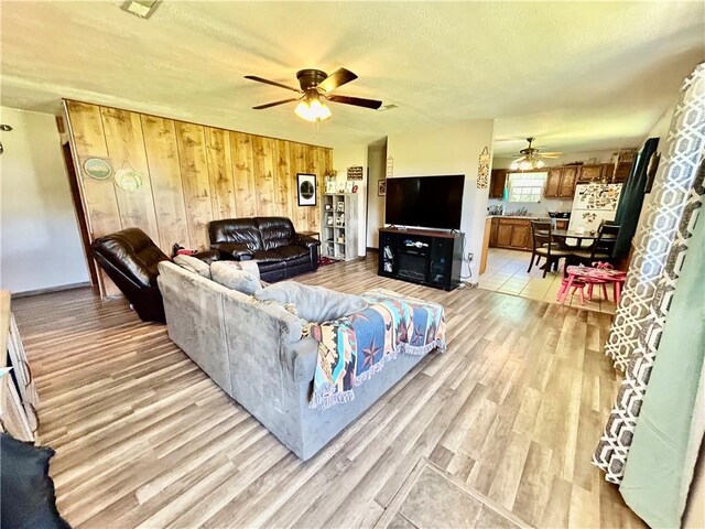 living room with light hardwood / wood-style flooring and wood walls