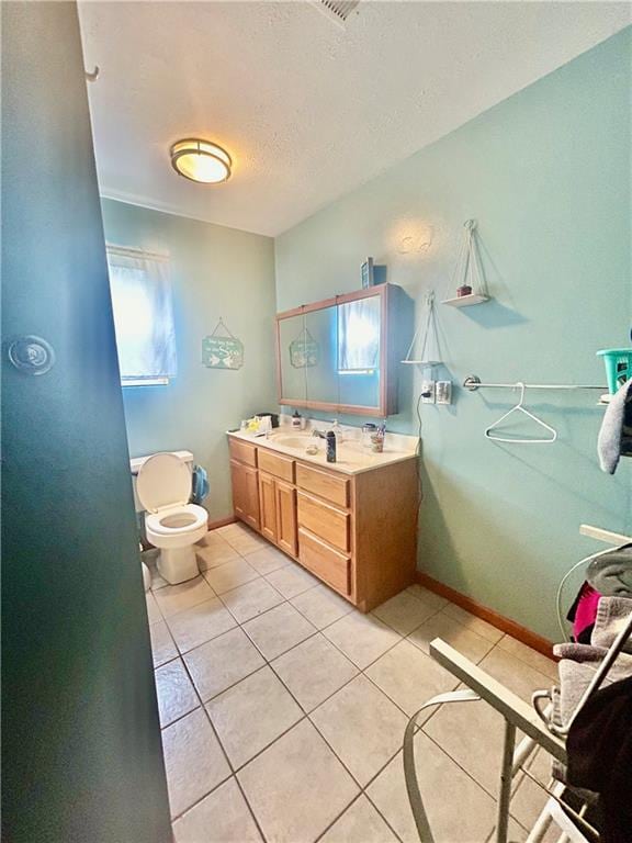 bathroom featuring tile patterned flooring, a textured ceiling, vanity, and toilet