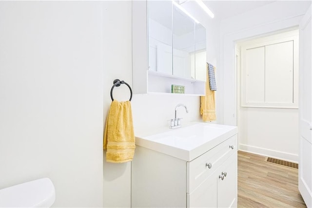 bathroom featuring vanity, hardwood / wood-style flooring, and toilet