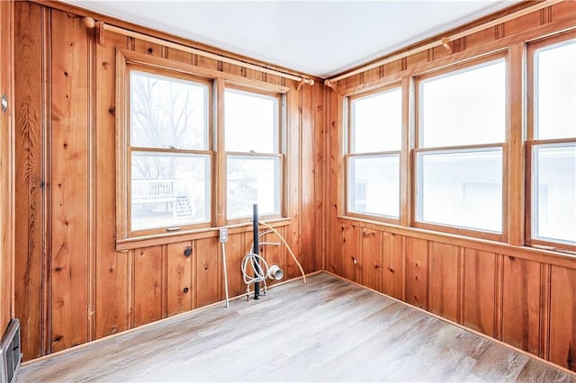 spare room with light hardwood / wood-style floors and wooden walls