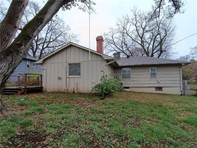 6204 Fairlane Dr, Kansas City, MO 64134 - back of property with a chimney, a deck, board and batten siding, and a yard