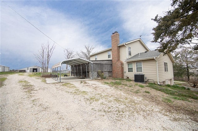 back of house with cooling unit and a carport