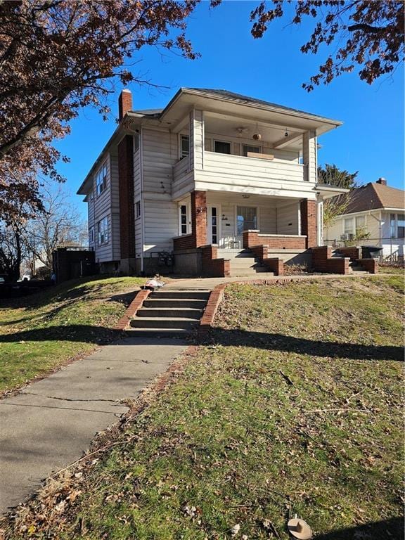 view of front facade with a balcony, covered porch, and a front yard